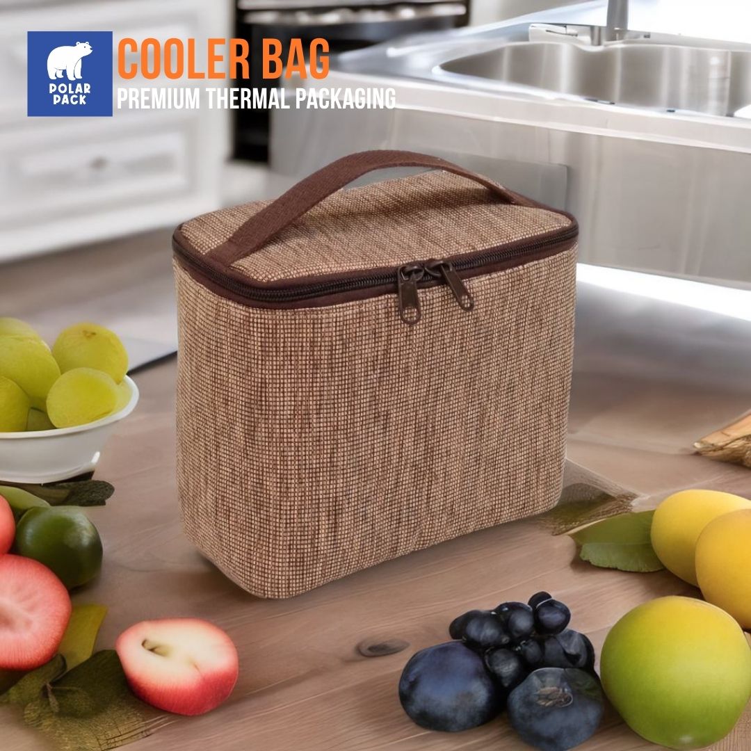 Cooler bag Polar Pack warna cokelat dengan resleting ganda dan handle, diletakkan di atas meja kayu dengan berbagai macam buah segar di sekitarnya.