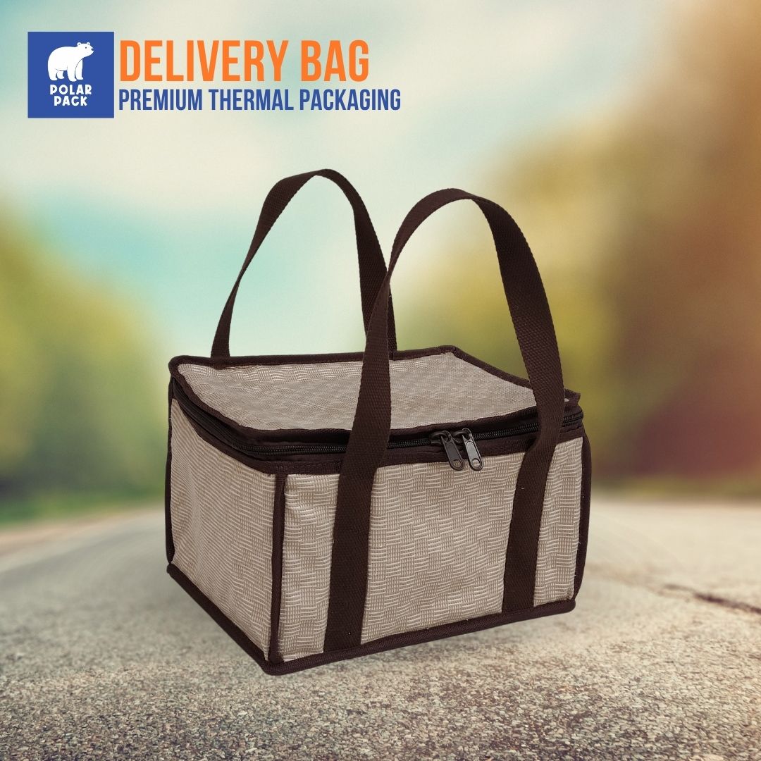 Tas delivery thermal Polar Pack berwarna krem dengan handle dan resleting cokelat, diletakkan di tengah jalan, ideal untuk pengiriman makanan.