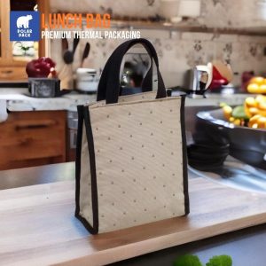 Tas bekal makan siang Polar Pack model jinjing warna krem dengan handle hitam, diletakkan di atas meja kayu, mampu menjaga suhu makanan tetap panas atau dingin.